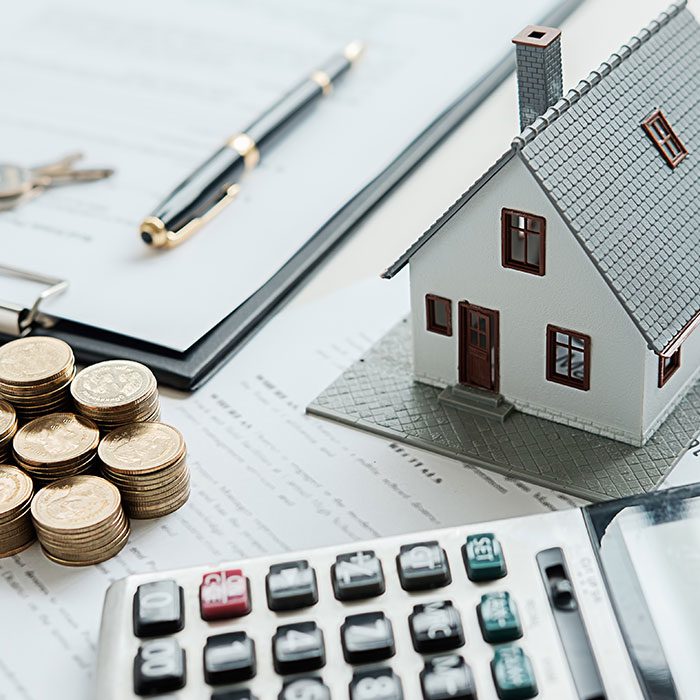 House model next to piles of coin and calculator