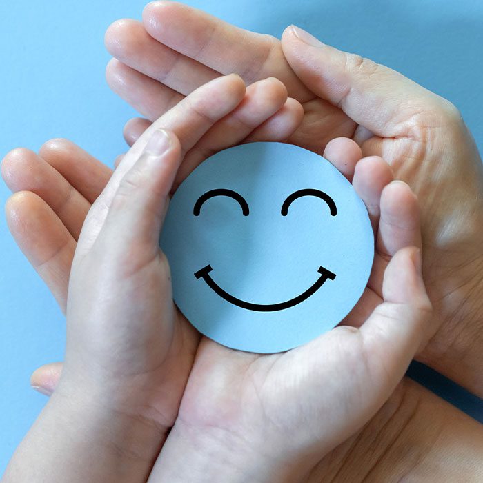 People hold blue smiley face in palms
