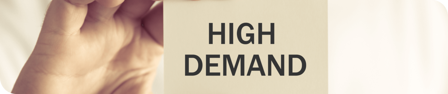 A person holding a card with 'high demand' written on it.