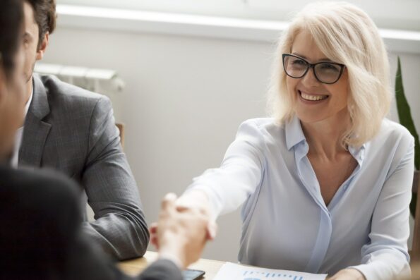 Female property investor shaking hands after making a deal at a meeting