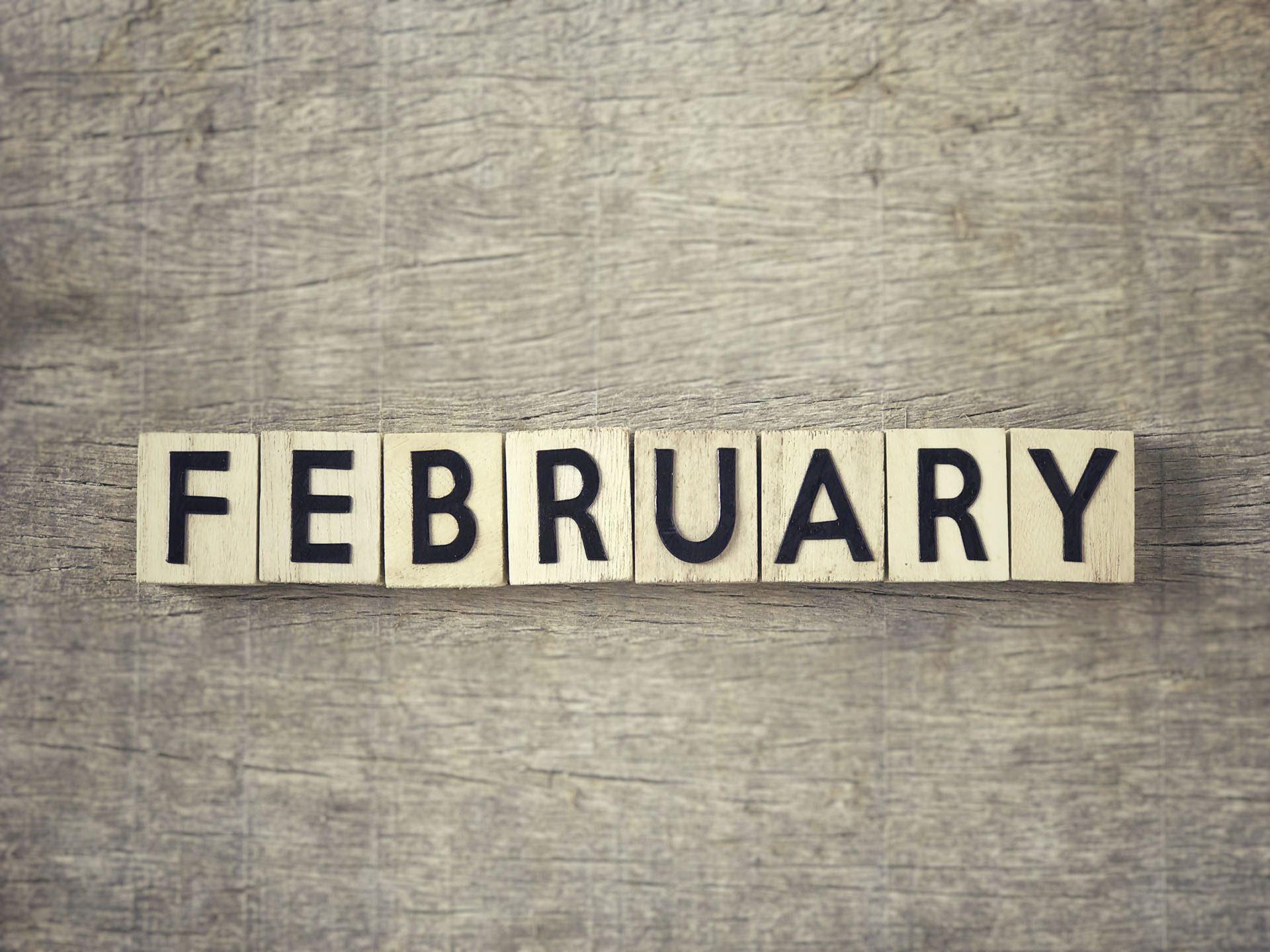 Motivational and inspirational word - ‘FEBRUARY’ written on wooden blocks and arranged on a wooden table.