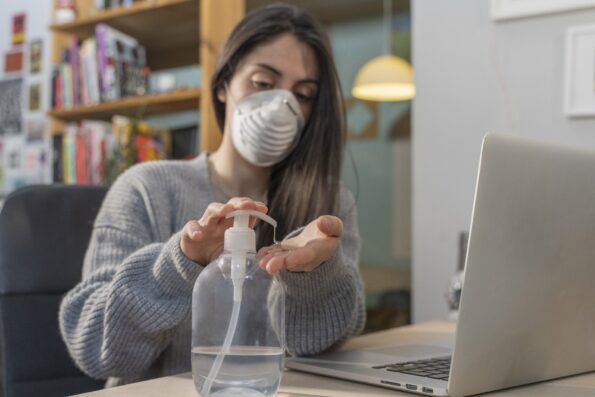 Woman with face mask puts hand gel on her hand - covid 19