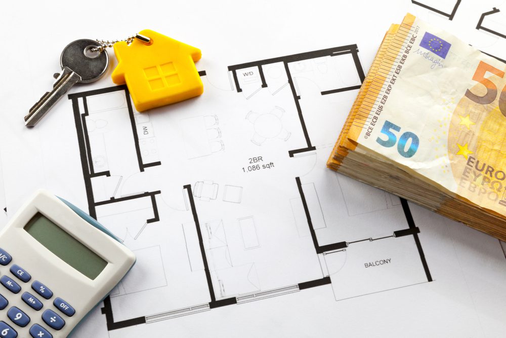 key, banknotes and calculator on top of a floor plan