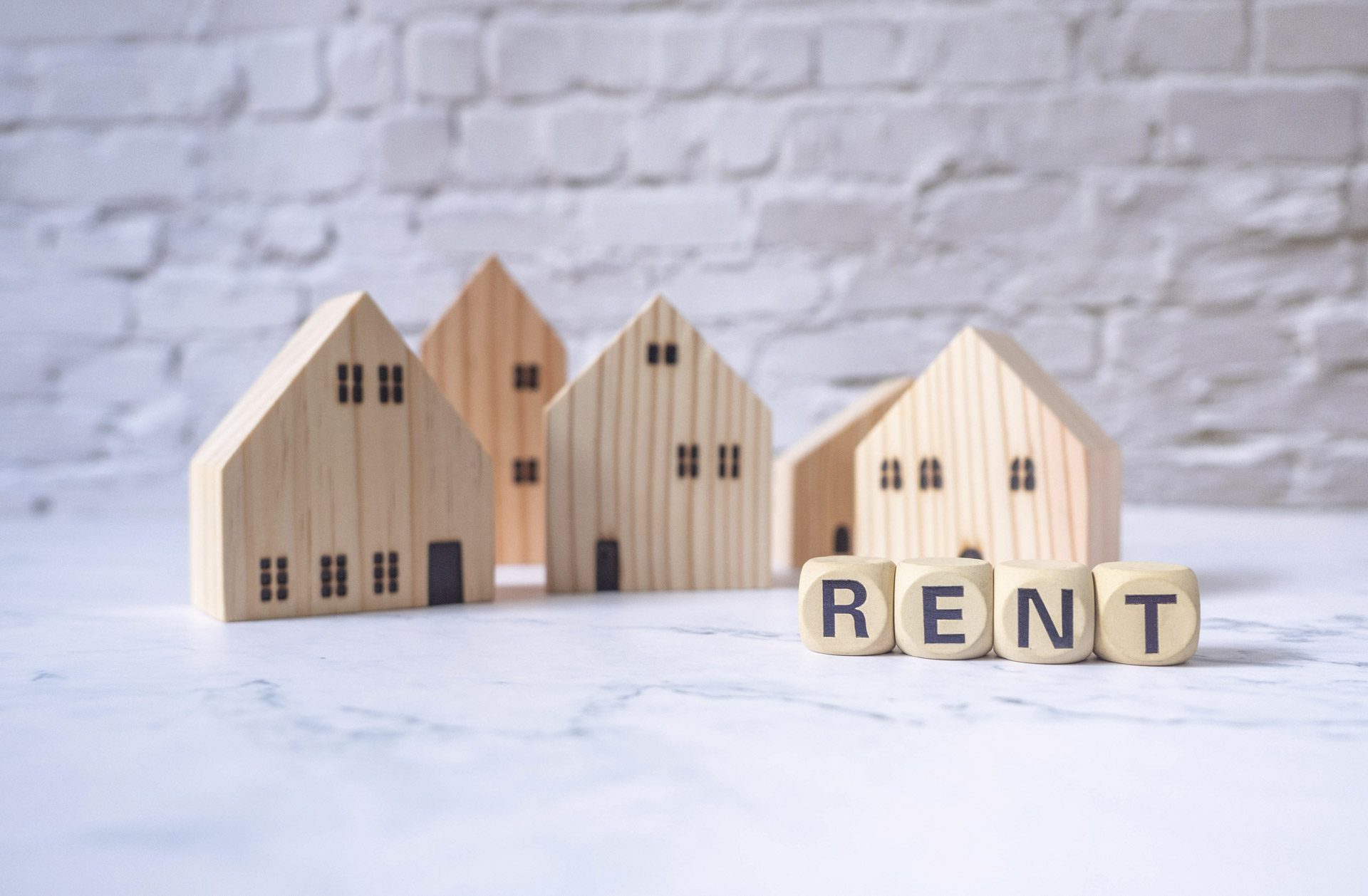 Miniature house and wooden blocks with the word rent on marble table.Real estate concept.Rent apartment. Property. Rental, renting home. Buying. Purchase housing