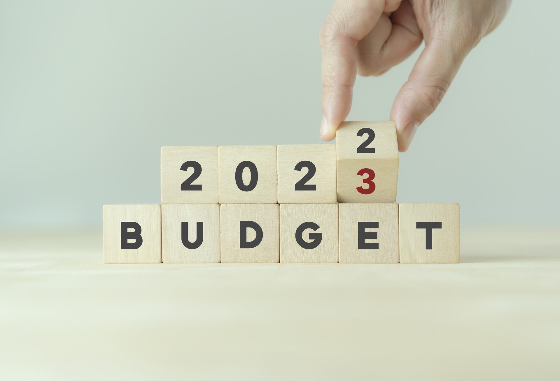 2023 Budget planning and allocation concept. Hand flips wooden cube and changes the inscription "BUDGET 2022" to "BUDGET 2023" with grey background, copy space. Use for banner and presentation.