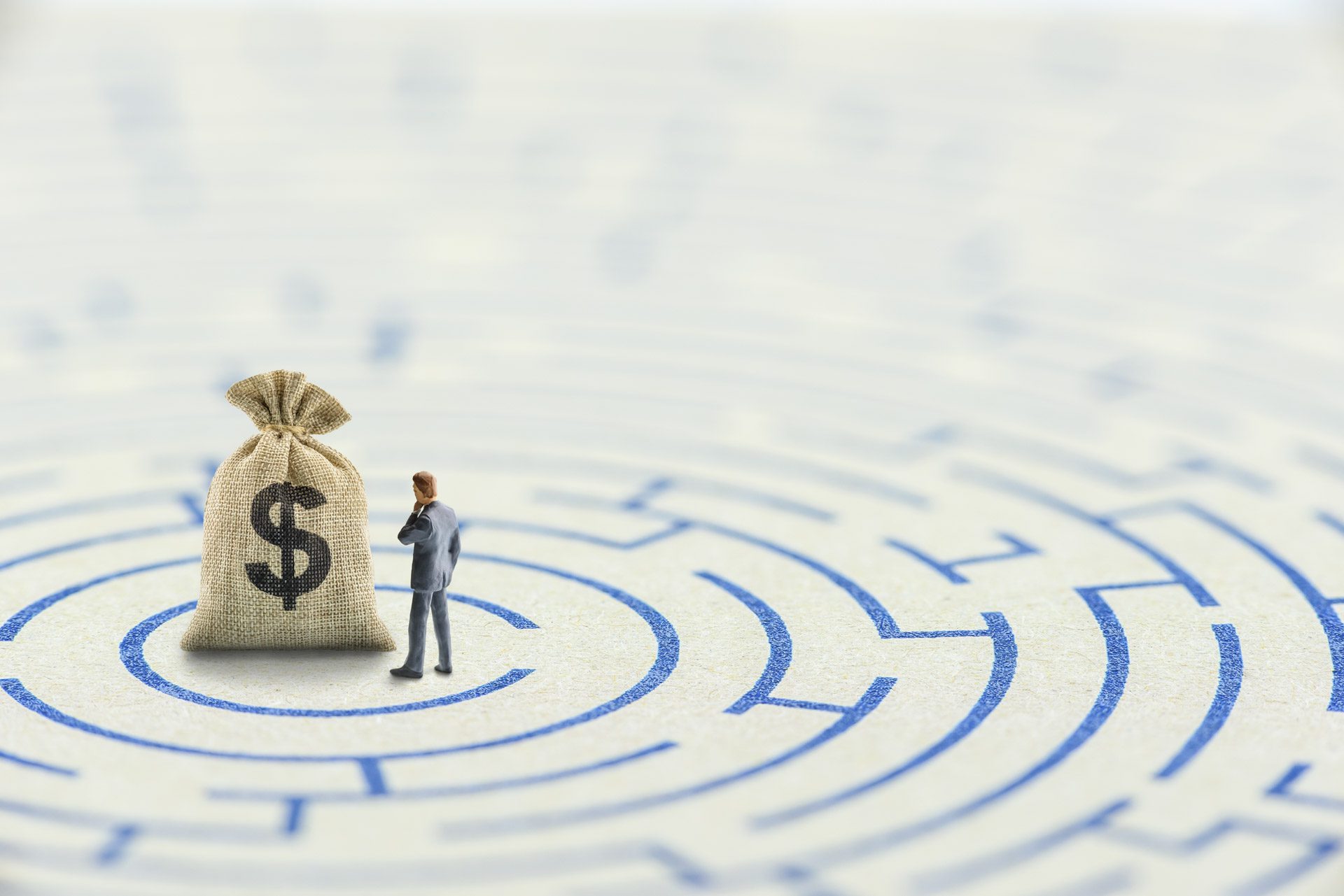 Reducing or overcome financial barrier, financial concept : US dollar bag on a maze puzzle with a businessman considers how to overcome financial difficulties. CFO wishes to avoid a financial crisis.