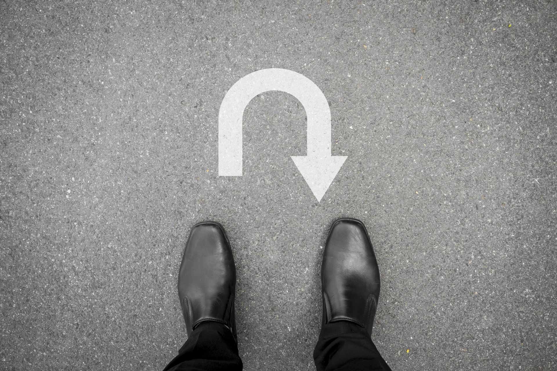 black shoes standing on the asphalt concrete floor in front of u turn symbol