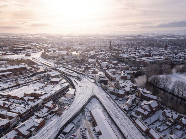 Aerial view of snow compromised rail and road networks. Snow, ice and winter weather conditions close railway links and shut roads causing transport delays and dangerous conditions.