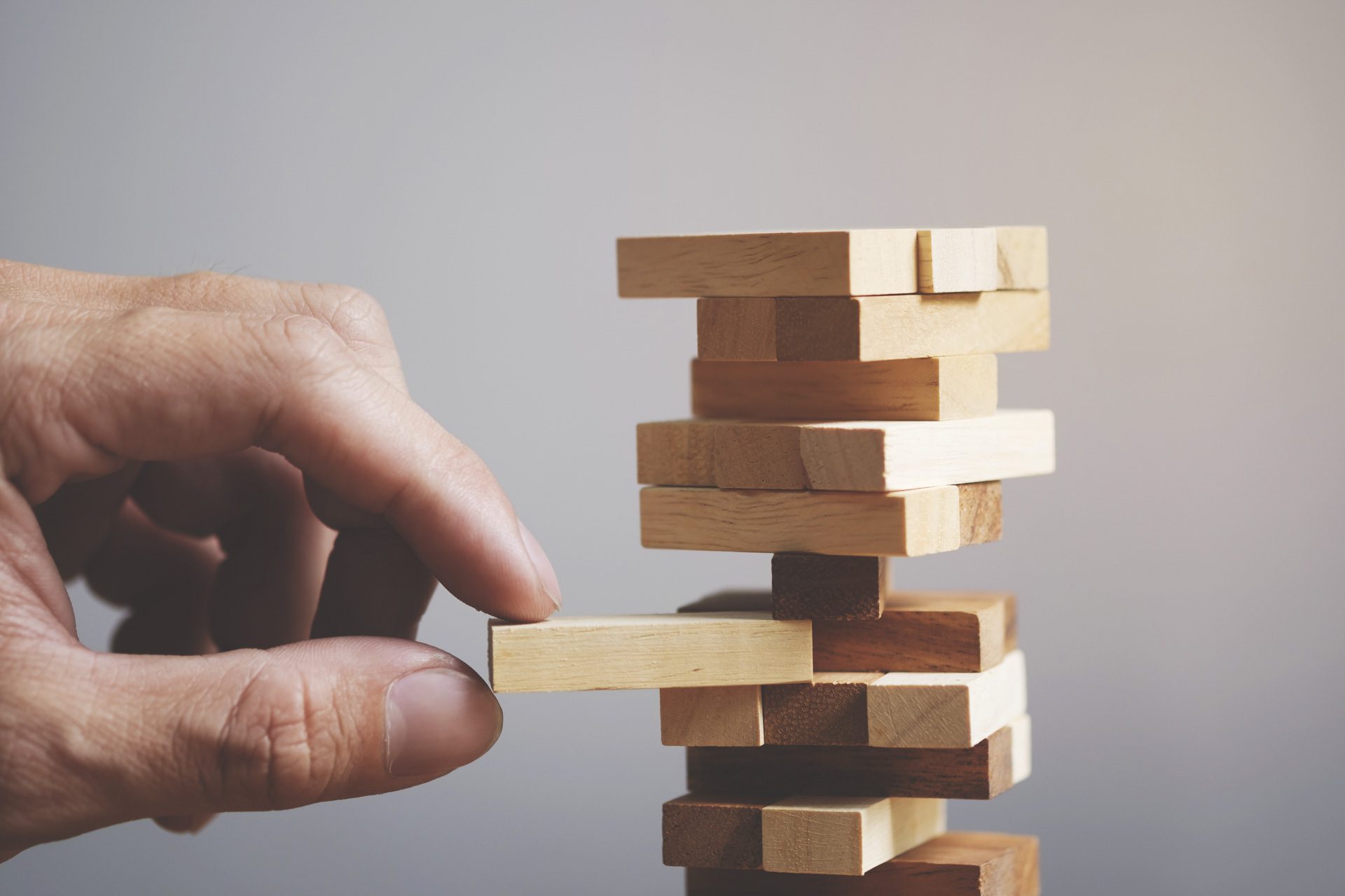 Hand of person playing jenga representing risk taking in investment