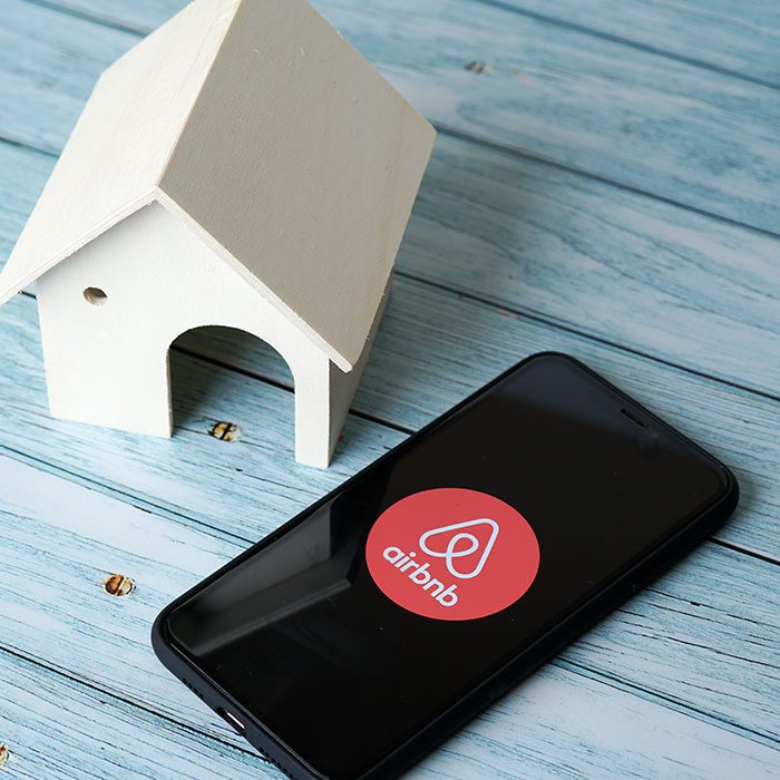 Airbnb app on a mobile phone right next to a house model