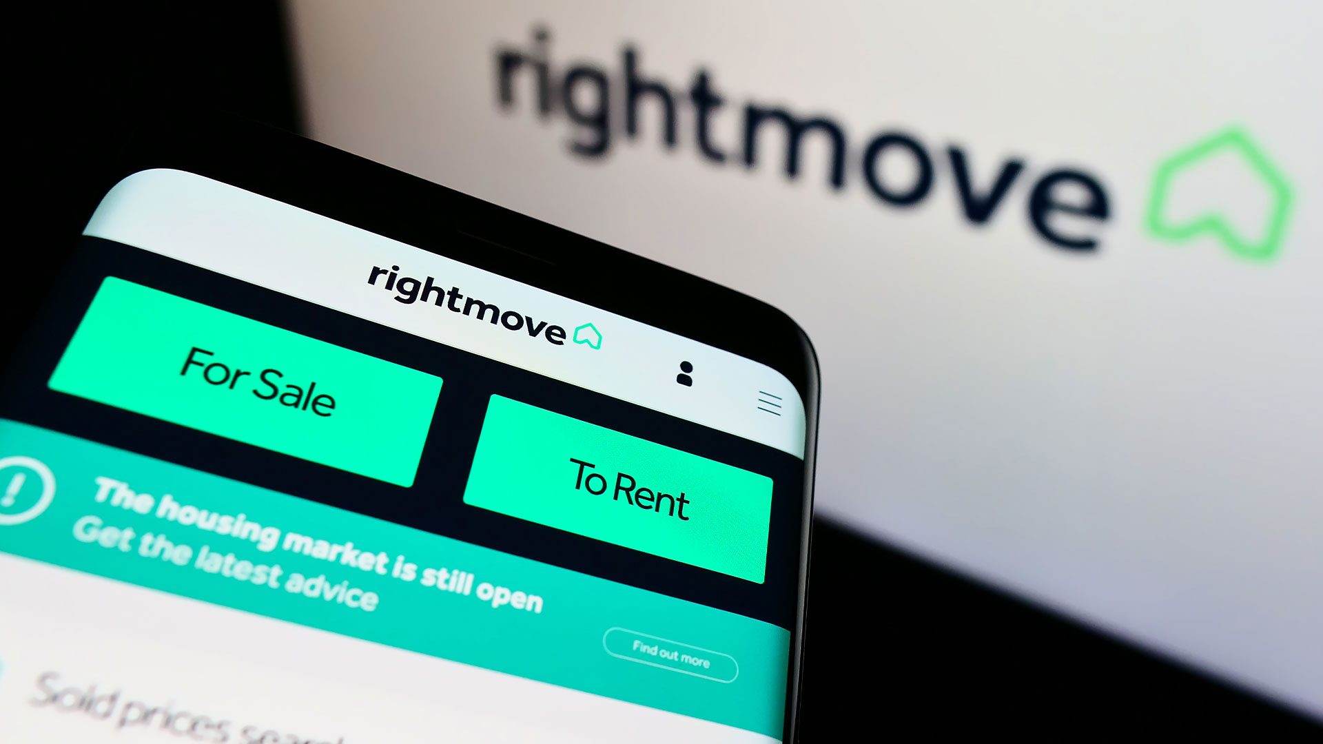 Person holding a phone with the Rightmove app opened