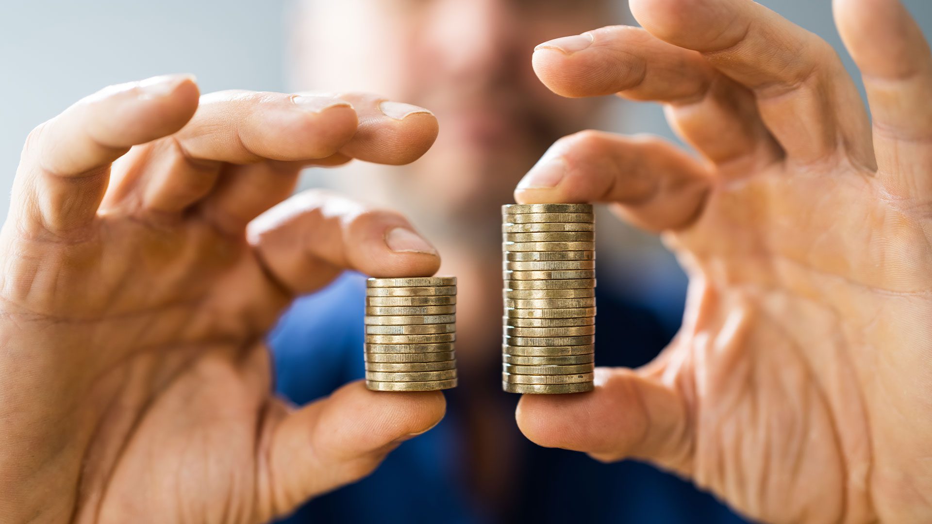 A person holding two piles of coin