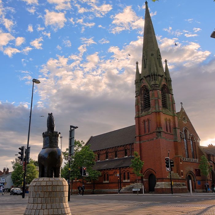 West Bromwich, UK. Statue called: 'I am King of the Castle' and The Catholic Church of Saint Michael and the Holy Angels on High Street - in the light of sunset.