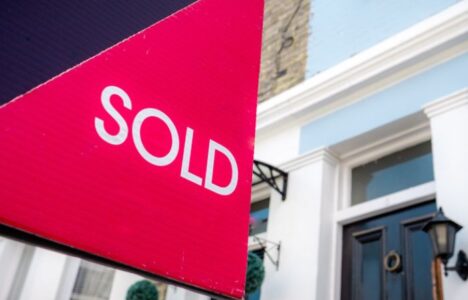 Estate agent sold sign with houses in background