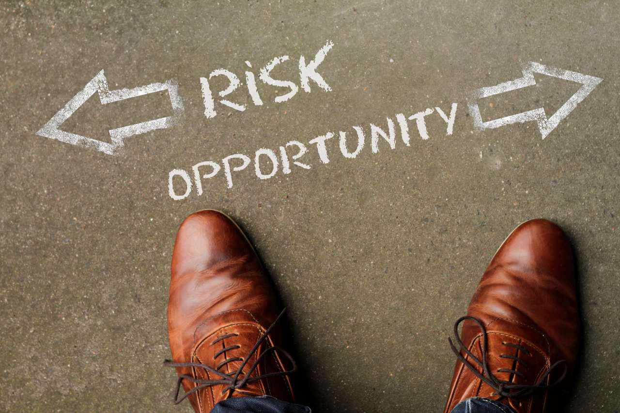 Top view on a man standing in front of the words Risk and Opportunity with arrows pointing to the left and right side