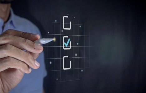 Hand holding a pen ticking a blue checkmark on a box on virtual screen