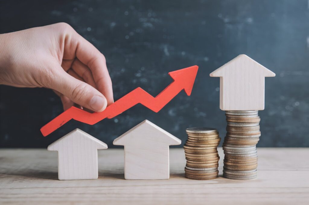 Hand holds red arrow pointing upwards beside house models