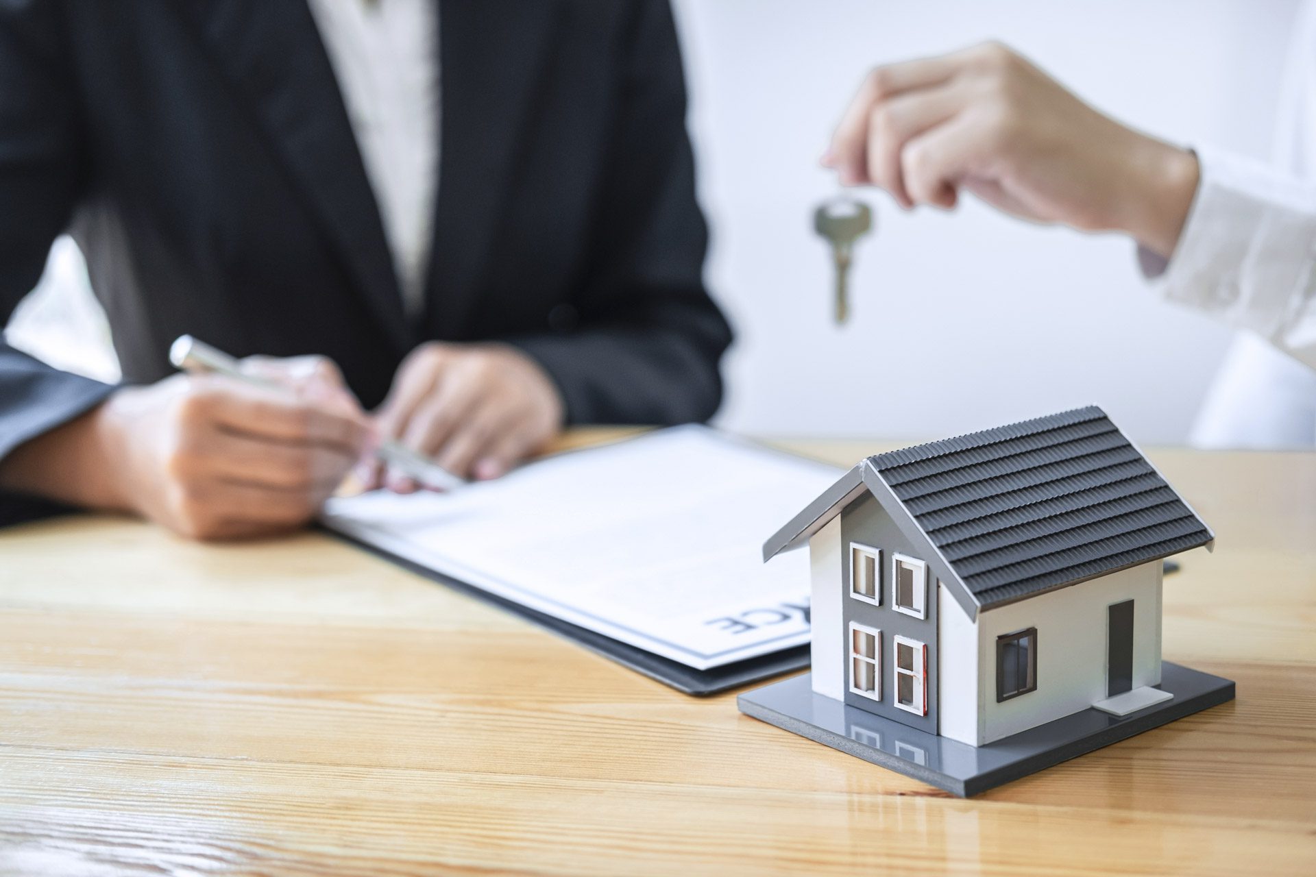 Sales agent giving house key to new client after signing agreement contract with approved property application form