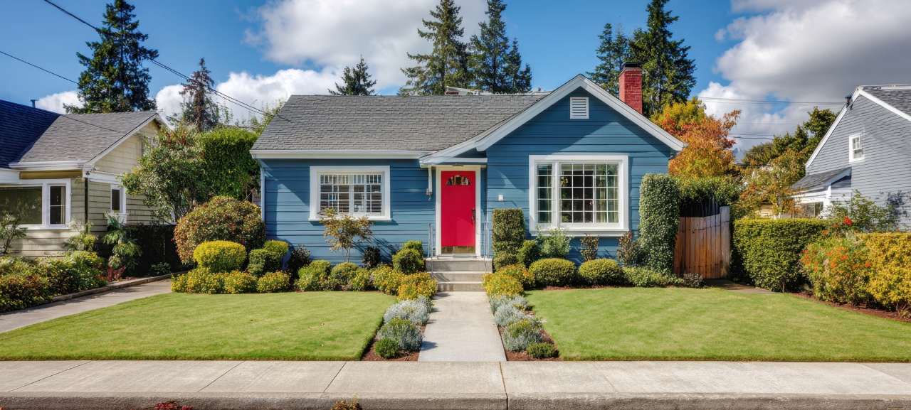 charming blue house with a vibrant red door and manicured garden