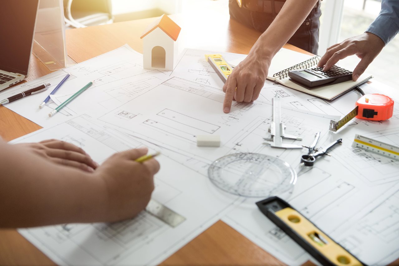 engineer using drawing compass with blueprint on desk