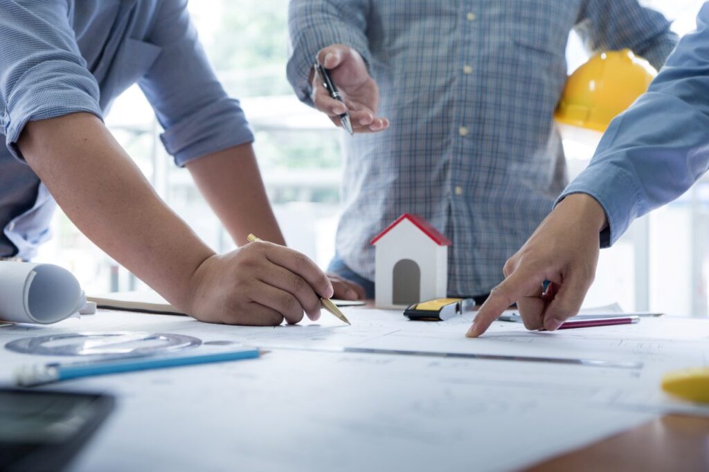 men discussing on desk with blueprint about new property project