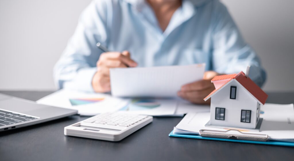 Stock image showing man at desk with paperwork and model of a house
