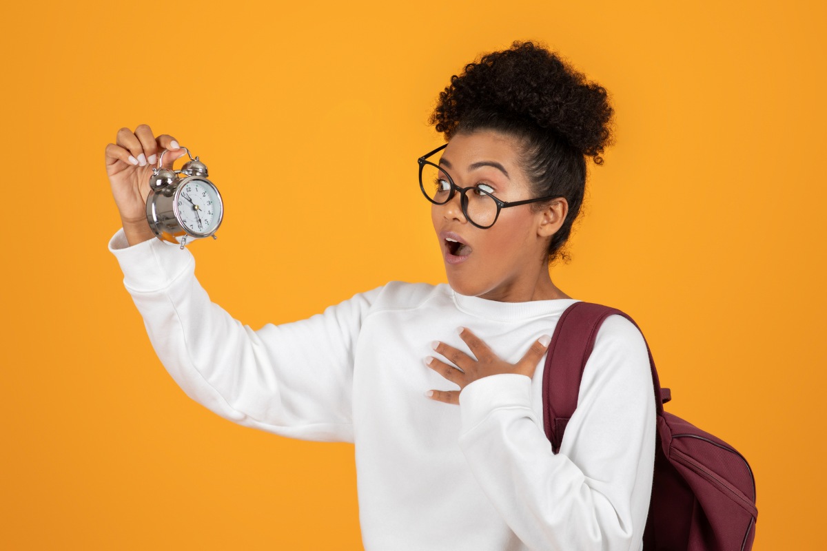 woman wearing glasses holding a clock