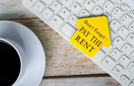 Don't forget, pay the rent text on yellow stick house shape on white keyboard