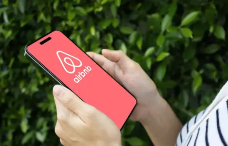 Arms of woman in striped top looking at Airbnb from a table device