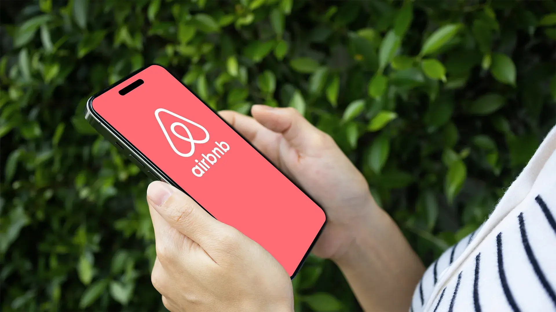 Arms of woman in striped top looking at Airbnb from a table device