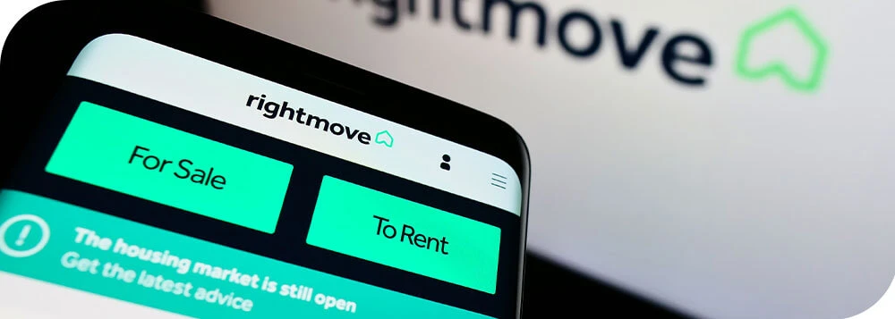 A phone with the Rightmove app and a computer showing the property portal's website for real estate market research